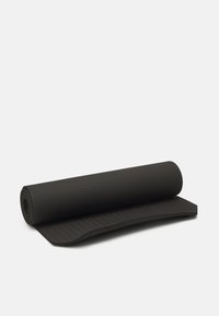 Esterilla de yoga negra, enrollada. Superficie texturizada con un lado liso. Forma cilíndrica compacta para un fácil almacenamiento.
