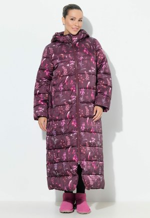 Lungo cappotto puffa viola con motivi floreali in rosa e bianco, dotato di cappuccio, chiusura con zip e tasche laterali. Indossato con stivali rosa.