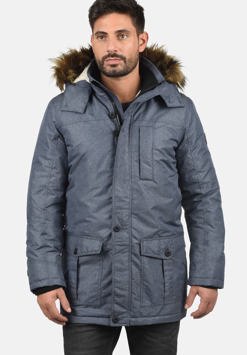 Blå isoleret parkacoat med hætte i faux fur, forlommer, knaplukning og en tekstureret overflade. Designet til varme og komfort.