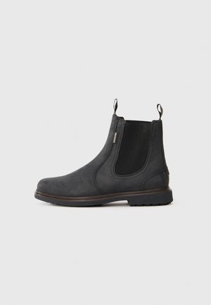 Bottines Chelsea noires avec un dessus en cuir lisse, des panneaux latéraux élastiques, des languettes de tirage et une semelle en caoutchouc texturée, présentant un design minimaliste.