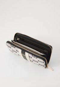 Black and white zip-around wallet featuring a textured canvas exterior, contrasting leather stripes, and multiple interior compartments.