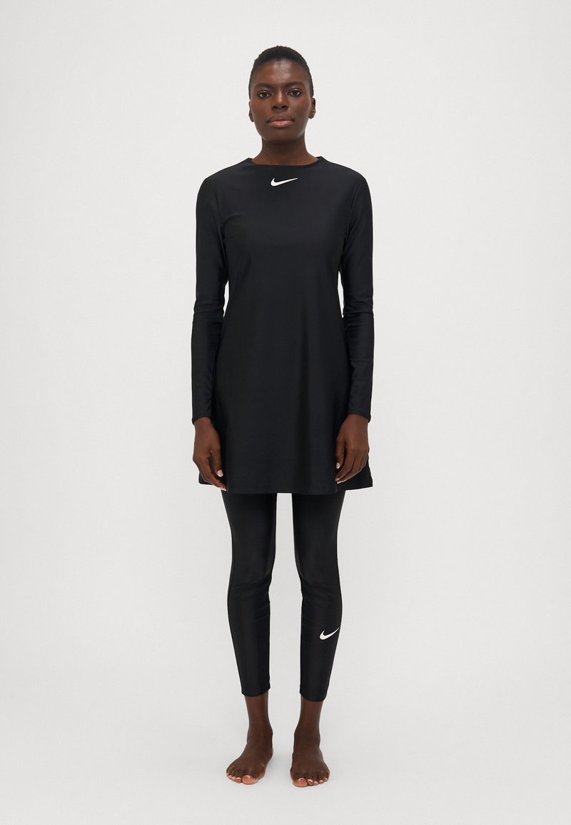 Juodas ilgomis rankovėmis tunikos suknelė su apvaliu iškirpimu, derinama su juodomis legging'ais. Pabrėžia baltus „Nike“ logotipo akcentus ant krūtinės ir kojų.