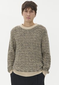 Pletena pulover s teksturiranim vzorcem v bež in črni barvi, z okroglim izrezom in rebrastimi manšeti ter robom, v sproščenem kroju.