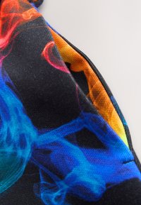 Primer plano de una tela con patrones coloridos que parecen humo en azul, rojo y naranja sobre un fondo negro.