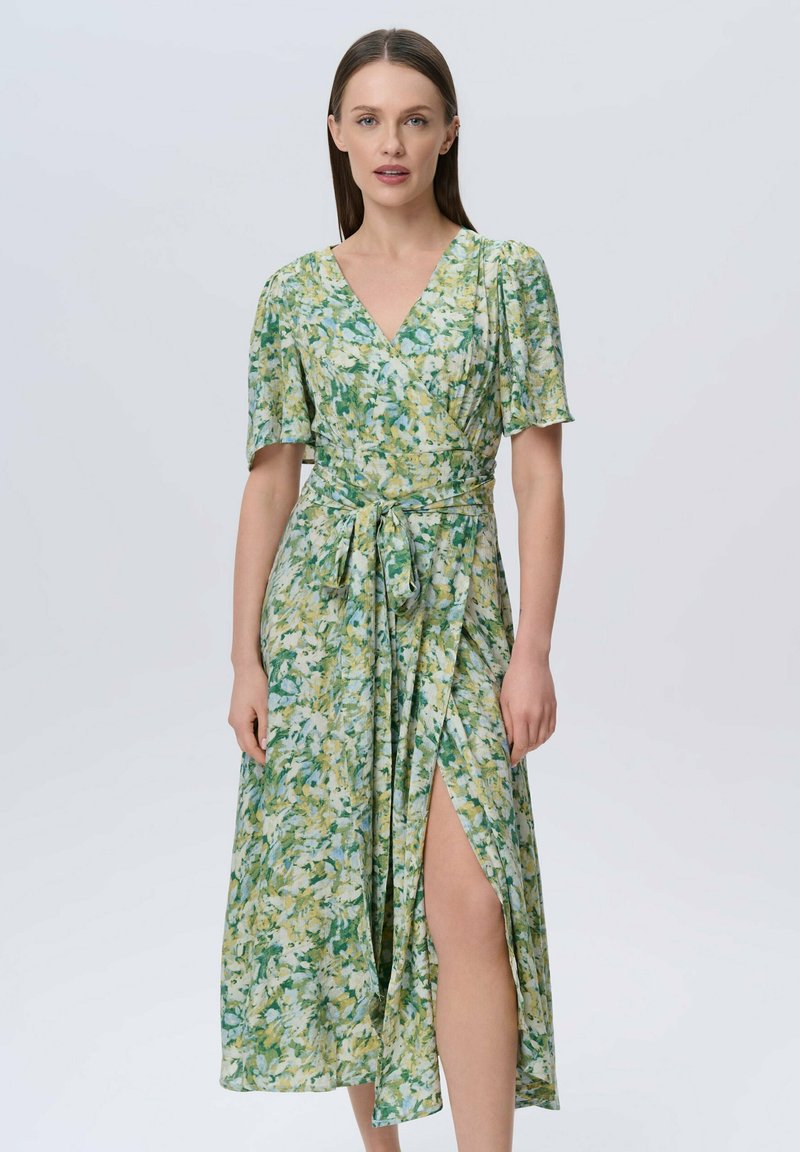 Blumenwäschekleid mit V-Ausschnitt, kurzen Puffärmeln und tailliertem Bund. Merkmale sind grün-gelbe abstrakte Muster und ein hoher Schlitz auf einer Seite.