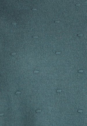 Tessuto in maglia color teal con una superficie testurizzata, caratterizzato da piccole gocce in risalto distribuite uniformemente. Materiale liscio ed elastico.