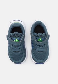 Blauwe sportschoenen met een bovenkant van mesh, grijze accenten en een witte zool. Kenmerkt zich door een groen logo en een gestructureerd patroon op de stof.