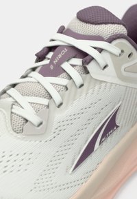Gros plan d'une chaussure de course Altra Torin 8 blanche et mauve avec des lacets blancs et une tige en tissu mesh.