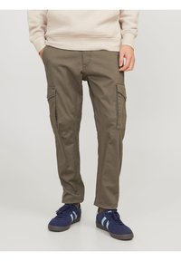 Olivgröna cargobyxor i bomull, med sidofickor, smal passform och subtila sömdetaljer. Bärs med blå sneakers.