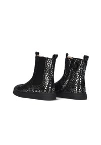 Zwarte enkellaarzen met een textuur en metallic afwerking, voorzien van een stippenpatroon. Elastische zijkanten en een zwarte rubberen zool zorgen voor flexibiliteit.