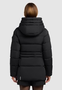 Jachetă puffer neagră cu glugă, având secțiuni capitonate, un guler înalt și un tiv posterior ușor mai lung. Material neted și design subtil.