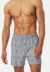 Boxers gris en tissu doux avec un motif de palmiers répété. Taille élastique avec un bouton à l'avant et des poches latérales.