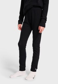 Svarta åtsittande leggings gjorda av ett mjukt, stretchigt material. Har en bekväm elastisk midjeband. Bärs med vita strumpor, minimal logosynlighet.