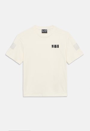 Jasnokremowy bawełniany t-shirt z okrągłym dekoltem, krótkimi rękawami, srebrną naszywką z logo EA7 oraz trzema równoległymi paskami na lewym rękawie.