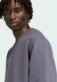 Szara bluza z prążkowanym detalem na ramionach, wykonana z miękkiego materiału. Posiada okrągły dekolt i subtelne logo na piersi.