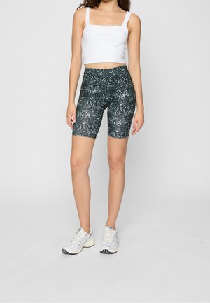Shorts da ciclista con motivo bianco e nero e vita alta, abbinati a un crop top bianco a scollo quadrato e scarpe da ginnastica.