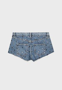 Shorts en denim avec bords effilochés, deux poches arrière, et des clous métalliques ronds uniformément espacés sur toute la surface.
