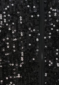 Juodas blizgančiais žvyneliais puoštas drabužis su tankia, atspindinčia paviršiaus tekstūra ir apvaliais žvyneliais. Dizainas apima vientisą juodą pamušalą ir lygią tekstūrą.