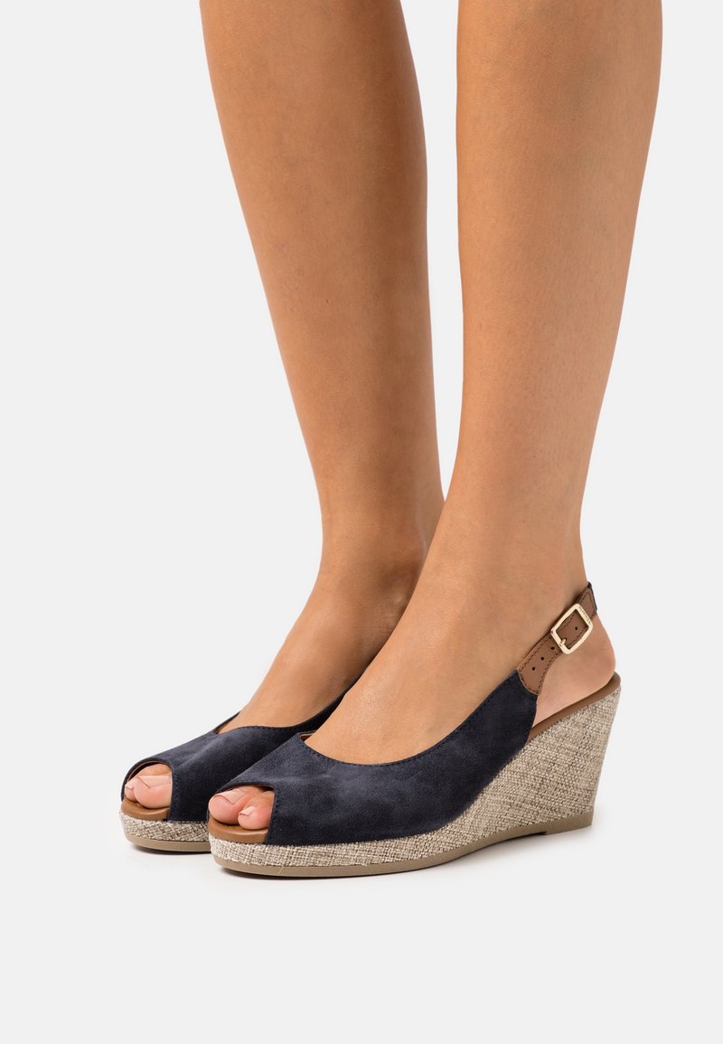 Sandales à talon compensé ouvertes en suède marine, avec un talon texturé similaire au jute et une sangle ajustable en boucle marron à l'arrière.