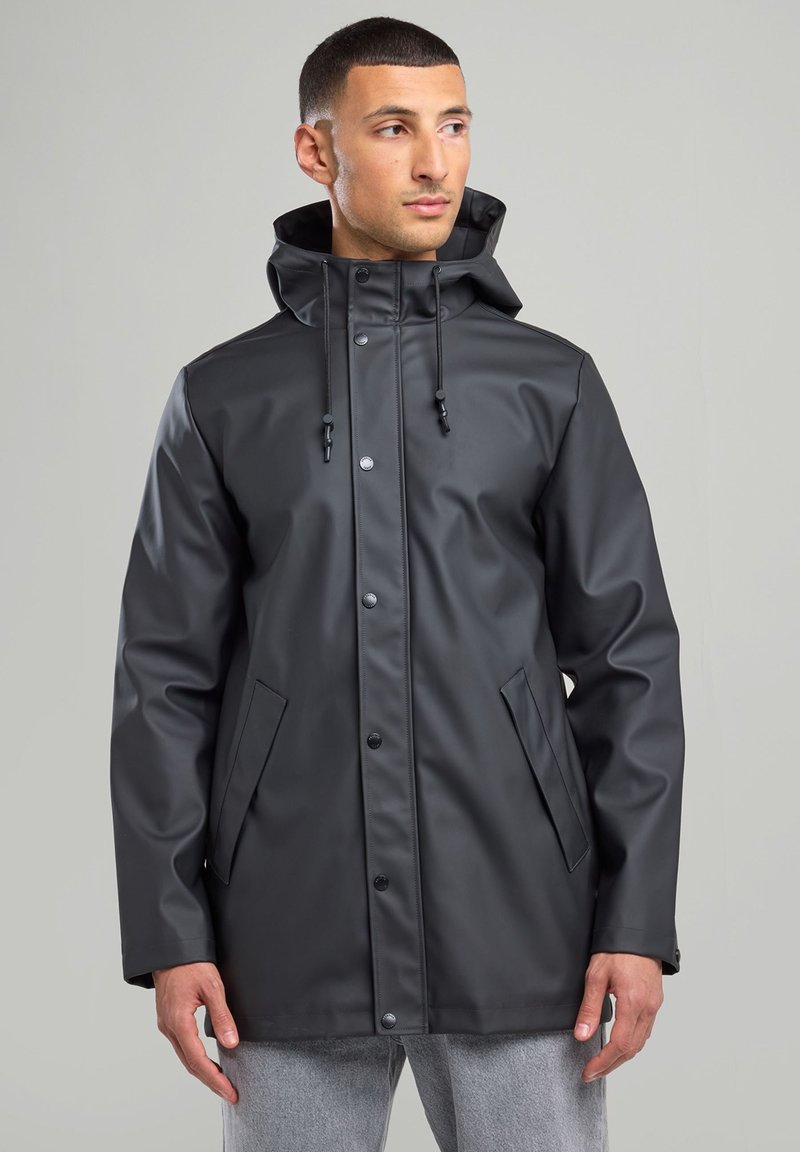 Black waterproof jacket with a hood, snap buttons, and two front pockets. Features a smooth texture and adjustable drawstring.