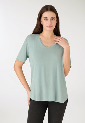 Miętowozielona koszulka z dekoltem w serek, wykonana z miękkiej tkaniny, z krótkimi rękawami i luźnym krojem z lekko zaokrąglonym dołem.