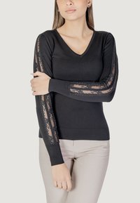 Maglione nero a maglia con scollo a V, con pannelli in pizzo trasparente sulle maniche e polsini a coste. Texture liscia e design aderente.