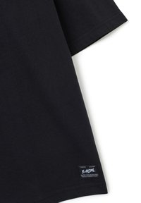 T-shirt nera in cotone con colletto tondo, maniche corte e etichetta cucita sull'orlo inferiore con testo bianco e dettagli del logo.