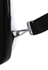 Black leather bag with a silver metal clip and a textured black fabric strap. The zipper is visible along the edge of the bag.
