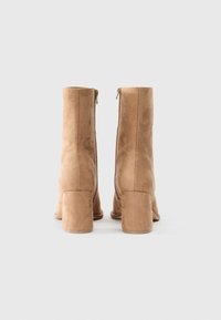 Suede ankle boots in light beige with a side zipper and a chunky heel. Smooth texture with seam detailing along the sides.