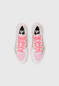 Pink and beige athletic shoes with mesh upper, three beige stripes, and bright pink laces. Features a textured white sole with perforations.