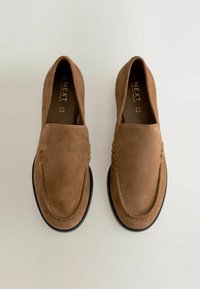 Des mocassins en daim marron avec un bout arrondi, des coutures visibles et des accents texturés le long des côtés. Semelle en caoutchouc noire.