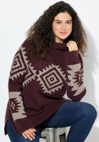 Weinroter Pullover mit hohem Kragen und geometrischen beigen Mustern an den Ärmeln. Weicher Stoff, lockere Passform und seitliche Schlitze am Saum.