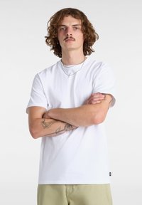 Witte katoenen t-shirt met korte mouwen en een rechte snit. Opvallende details zijn een klein logo aan de zoom en zichtbare tatoeages op de armen.