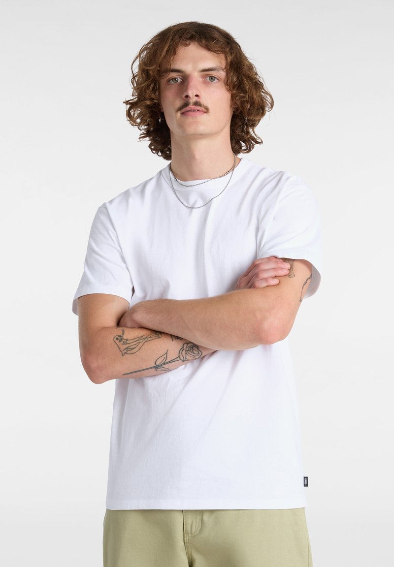 Witte katoenen t-shirt met korte mouwen en een rechte snit. Opvallende details zijn een klein logo aan de zoom en zichtbare tatoeages op de armen.