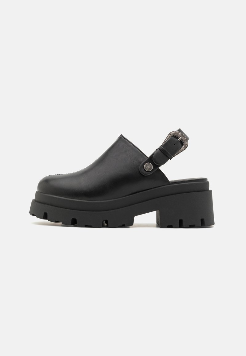 Sabot en cuir noir avec sangle ajustable et semelle en caoutchouc épaisse, présentant une finition texturée et un détail de boucle sur le côté.