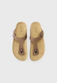 Sandales marron avec une texture en daim, présentant un design à l'entre-doigt, une boucle ajustable et un accent noir contrastant sur la semelle.