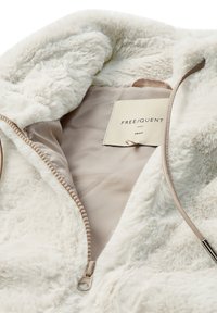 Hellbeige Kunstfell-Jacke mit Reißverschluss und satinierter Innenauskleidung, die ein kleines Markenlabel und eine strukturierte Oberfläche aufweist. Der Reißverschluss ist mit einem dünnen Kordelzug versehen.