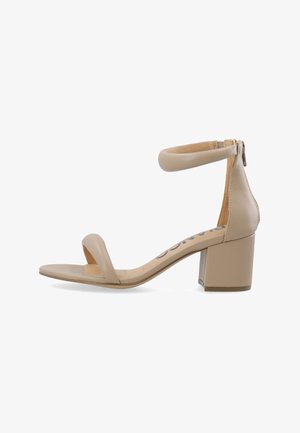 Sandal de tacón bloque beige con un acabado liso, puntera abierta y una correa en el tobillo que cuenta con un cierre de cremallera. Diseño simple y minimalista.