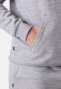 Felpa grigia mélange con tasca a marsupio, polsini a costine e accento con la bandiera svedese sull'orlo. Tessuto morbido e vestibilità casual.
