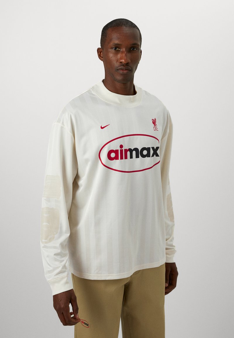 T-shirt a maniche lunghe in jersey color crema con logo rosso, strisce verticali e dettagli testurizzati sulle maniche. Marchio Nike sul petto.