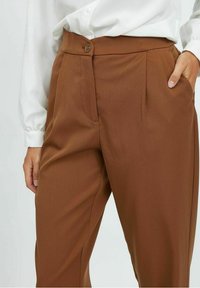 Ruske suknje krojene od glatke tkanine, s pojasom na dugme, bočnim džepovima i prednjim plisama.