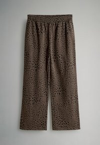 Bruna vida byxor med svart oregelbundet leopardmönster och elastisk midja, visade mot en enfärgad ljusgrå bakgrund.