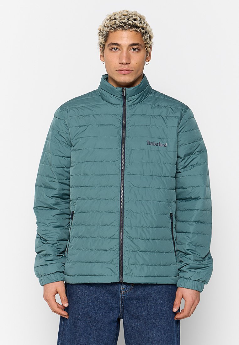 Türkise gesteppte Jacke mit hohem Kragen, Reißverschluss vorne und Seitentaschen; verfügt über dezentes Branding auf der Brust und gerippte Bündchen.