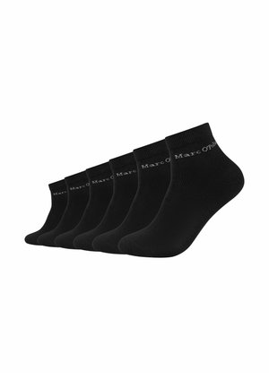 Sei paia di calzini neri alla caviglia allineati fianco a fianco con il marchio "Marc O'Polo" vicino al polsino.