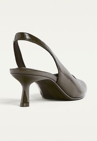 Sandal con tacco in finta pelle marrone, con punta affusolata, caratterizzata da una cinghia curva e un tacco a spillo di 6 cm a forma conica. Superficie liscia e testurizzata.