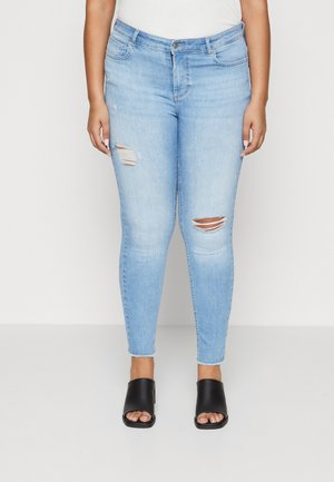 Ljust blå skinny jeans med slitna knädetaljer och fransade fållar. Matchat med svarta öppna tofflor.