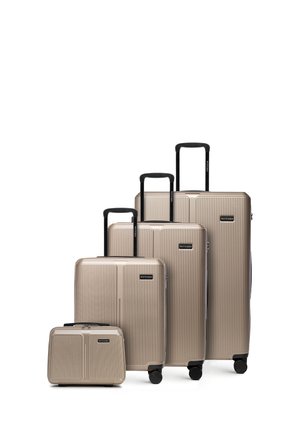 Set van vier beige harde koffers met zwarte uitschuifbare handgrepen en wieltjes, variërend van kleine handbagage tot grote ingecheckte maten.