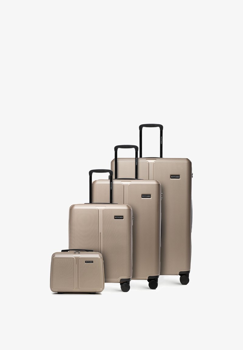 Ensemble de quatre valises rigides beiges avec poignées télescopiques noires et roulettes, allant de petites tailles cabine à grandes tailles enregistrées.