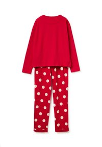 Červený bavlněný top s dlouhým rukávem spojený s červenými kalhotami s bílými puntíky. Oba kousky mají volnější střih a hladkou texturu.