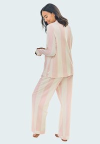 Jasnoróżowy i kremowy zestaw odzieży dresowej w paski z długimi rękawami i luźnymi spodniami, wykonany z miękkiego bawełnianego materiału.